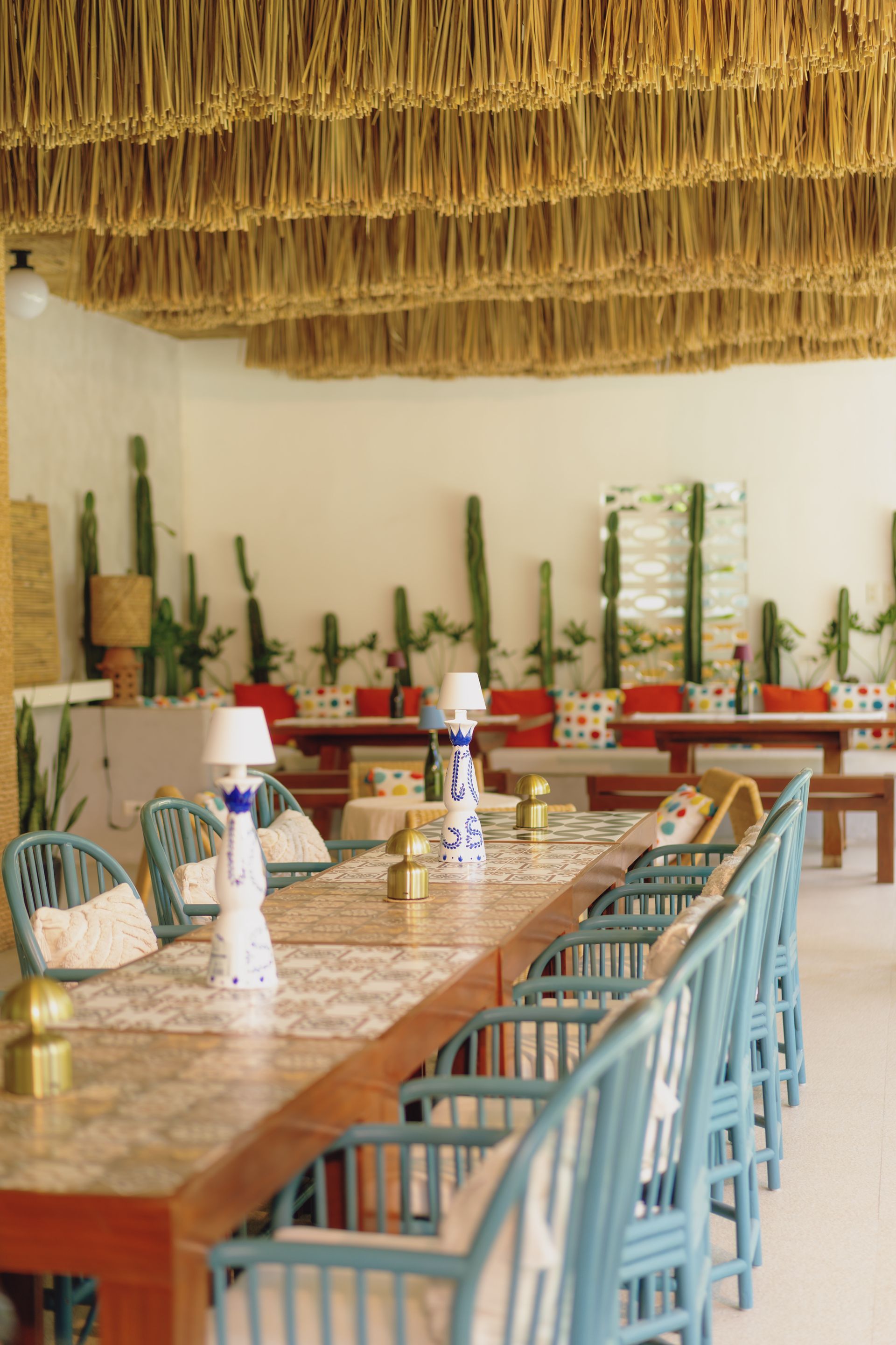 A dining room with tables and chairs and a thatched ceiling