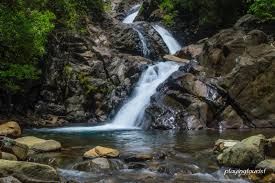 A waterfall is surrounded by rocks and trees in the middle of a river.