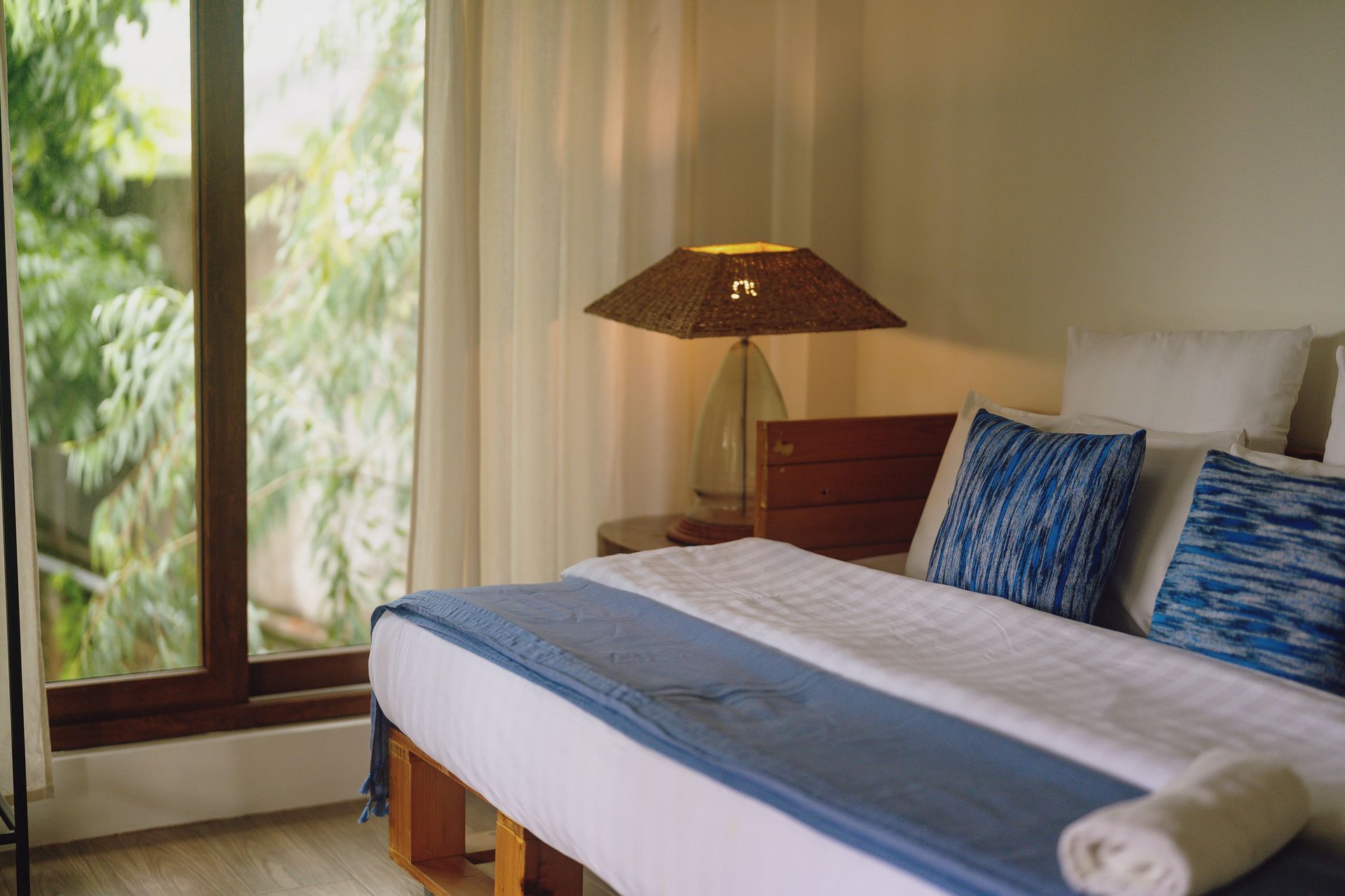 A bedroom with a king size bed , a lamp , and a large window.
