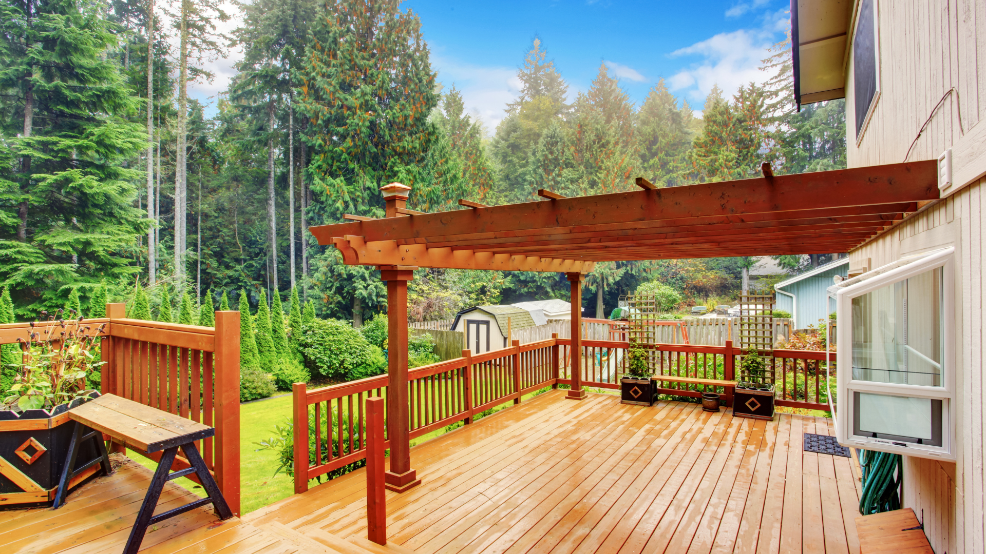 A beautiful photo of a deck on the back of a house. The deck is surrounded by trees and greenery