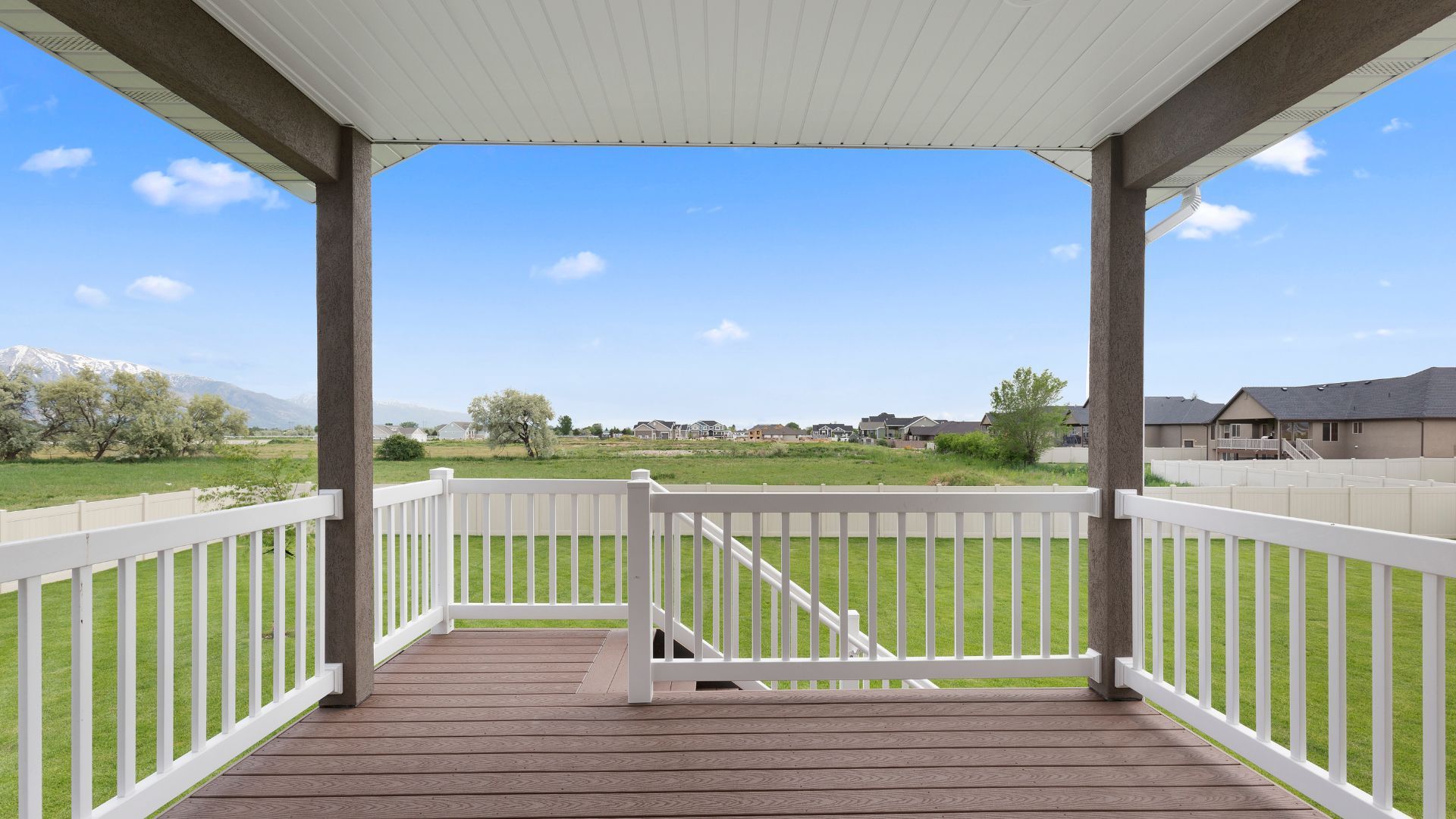 Covered deck in Lexington, KY with white railings and a scenic view of green fields and mountains.
