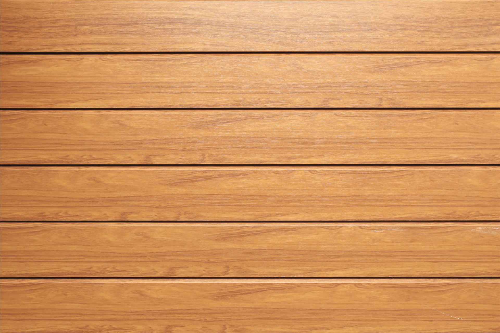 A close-up image of a well-maintained wooden deck with a rich golden stain in Lexington, Kentucky. The deck boards are aligned horizontally, showing a smooth, polished surface and the natural wood grain. The seamless finish suggests professional quality workmanship, emphasizing the beauty of outdoor wooden construction and care.