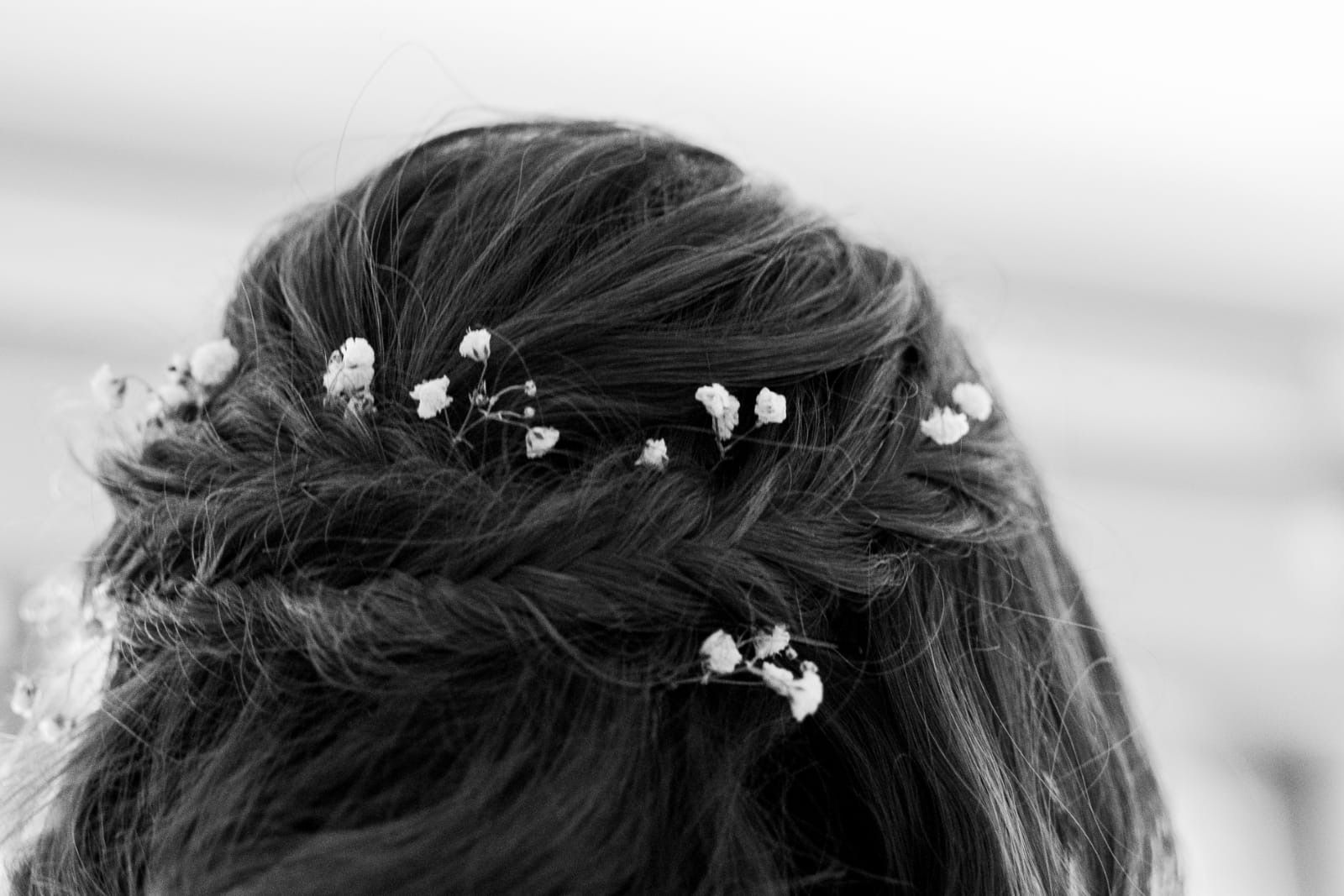 Acconciatura intrecciata decorata con piccoli fiori bianchi.