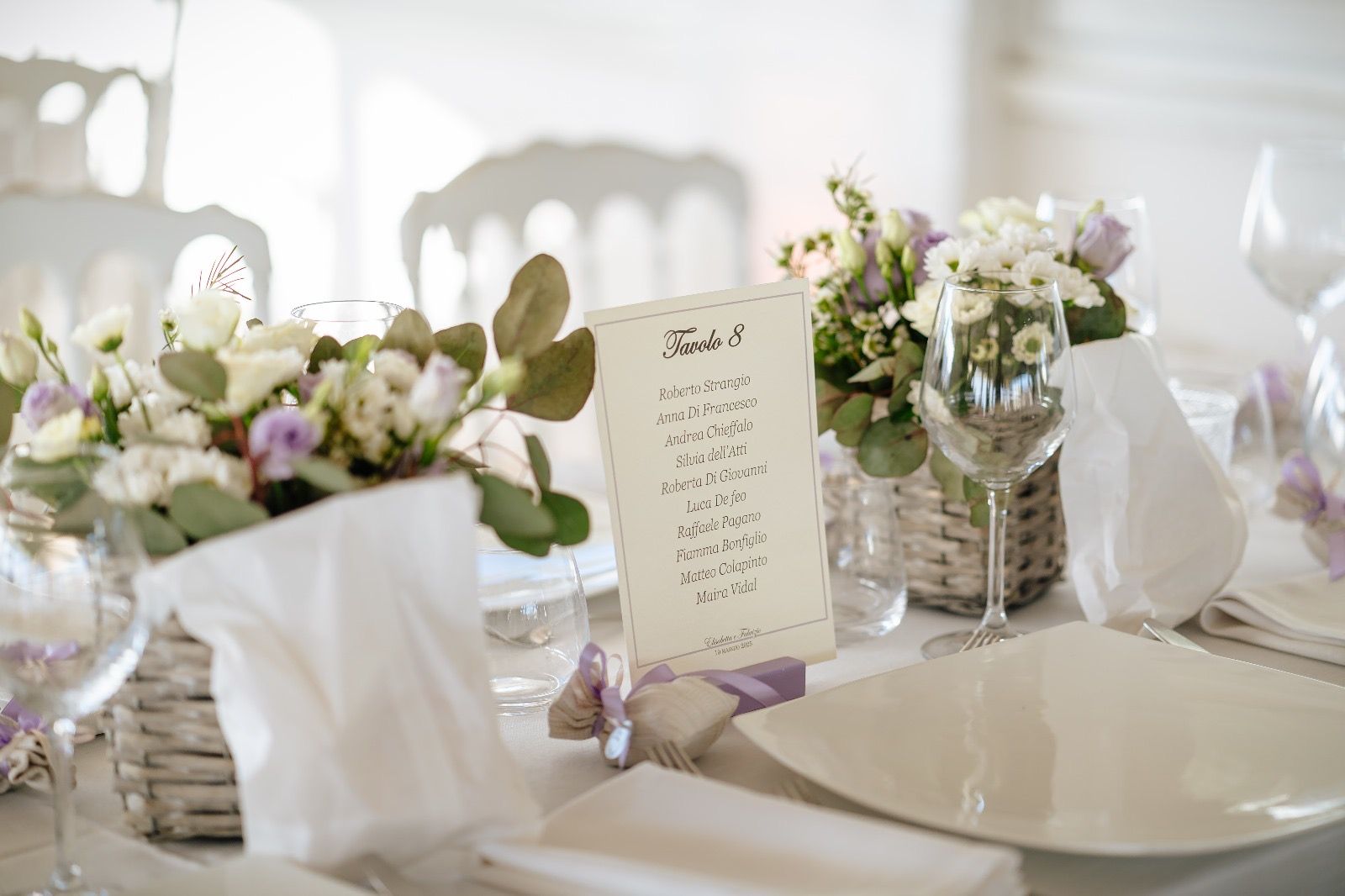 Elegante apparecchiatura della tavola con composizioni floreali, menù e bicchieri.