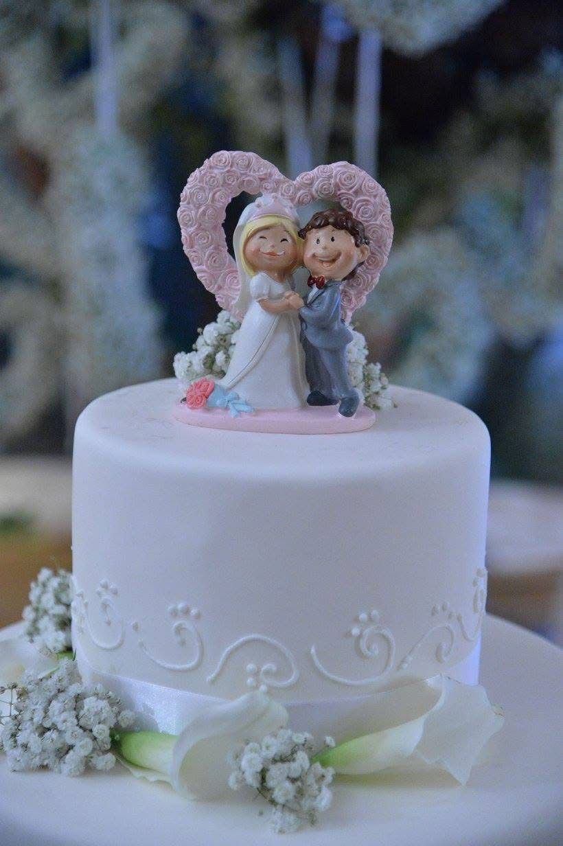 Torta nuziale con decorazione a forma di cuore e raffigurante gli sposi.