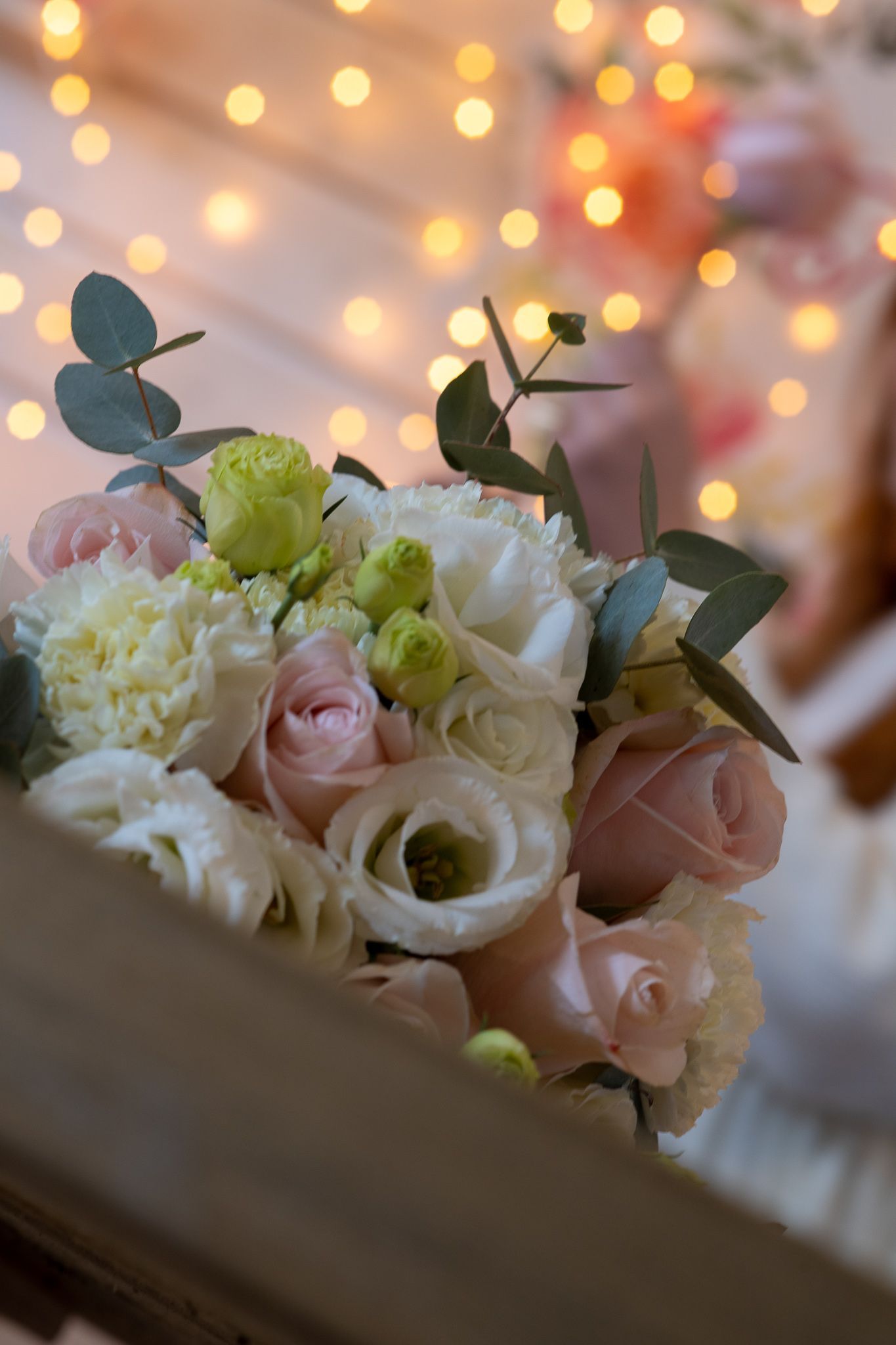 Bouquet di fiori bianchi, rosa e verdi con luci sfocate sullo sfondo.