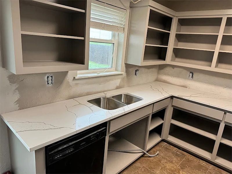 Bathroom with a dark blue double vanity, marble countertop, and black fixtures; a large mirror hangs above the sinks.