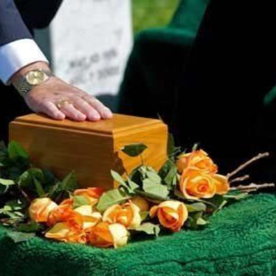 Urn being placed on top of a casket for an in-ground burial