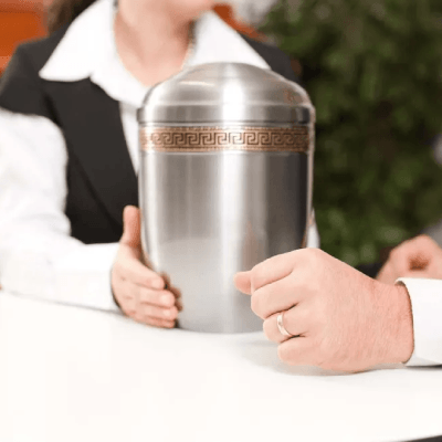 Funeral urn being handed off from a funeral home worker to a family member