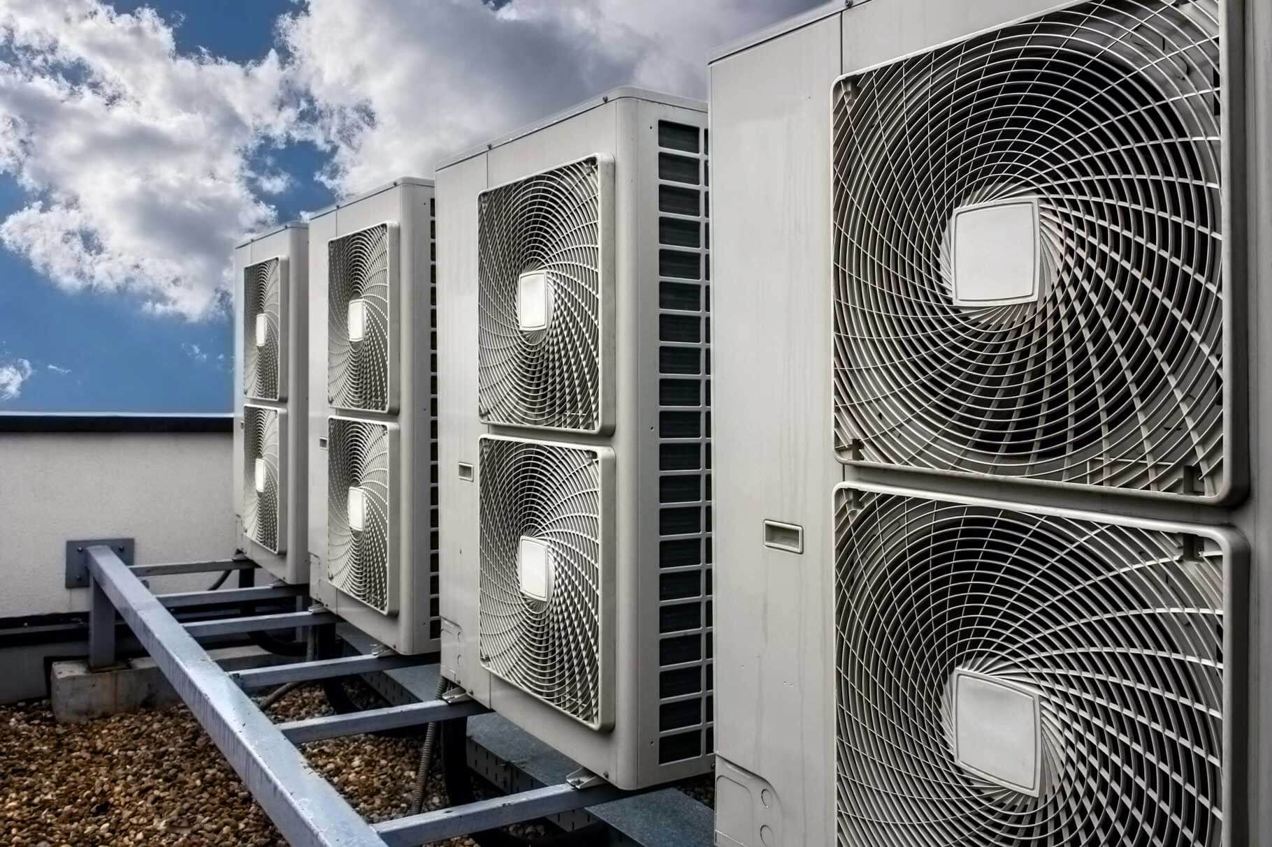 A row of air conditioners are sitting on top of a building.