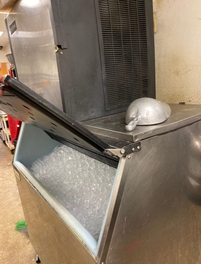 A person is scooping ice out of an ice machine.