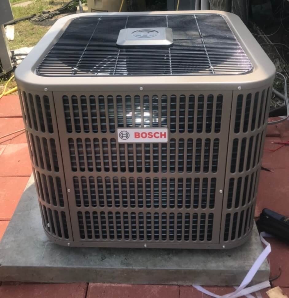 A bosch air conditioner is sitting on a brick floor