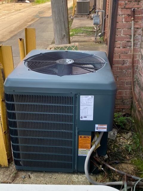 An air conditioner is sitting outside of a brick building