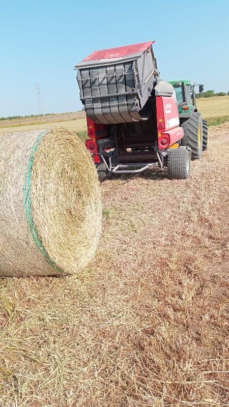 Un trattore sta imballando il fieno in un campo.