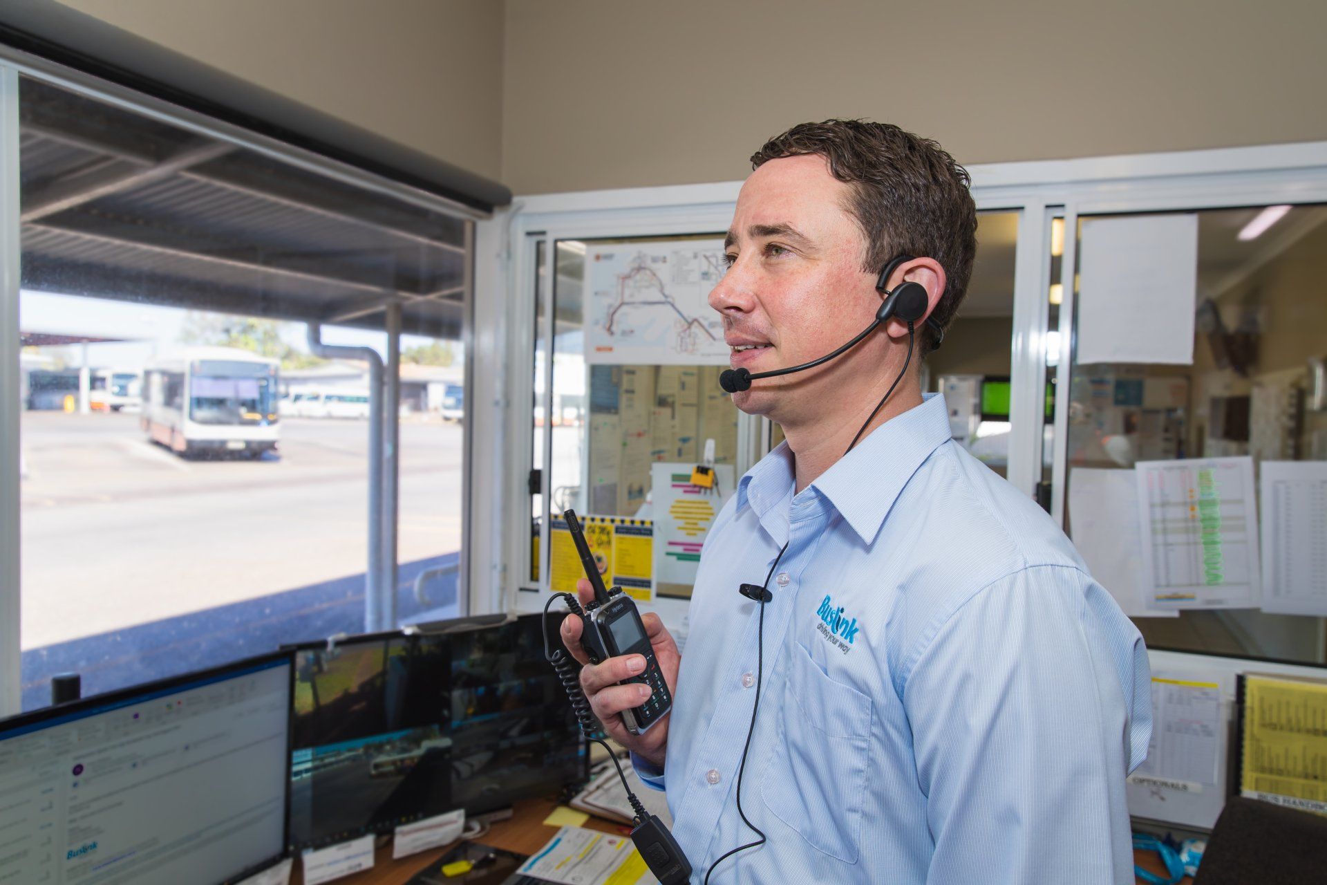 A man is wearing a headset and holding a walkie talkie.