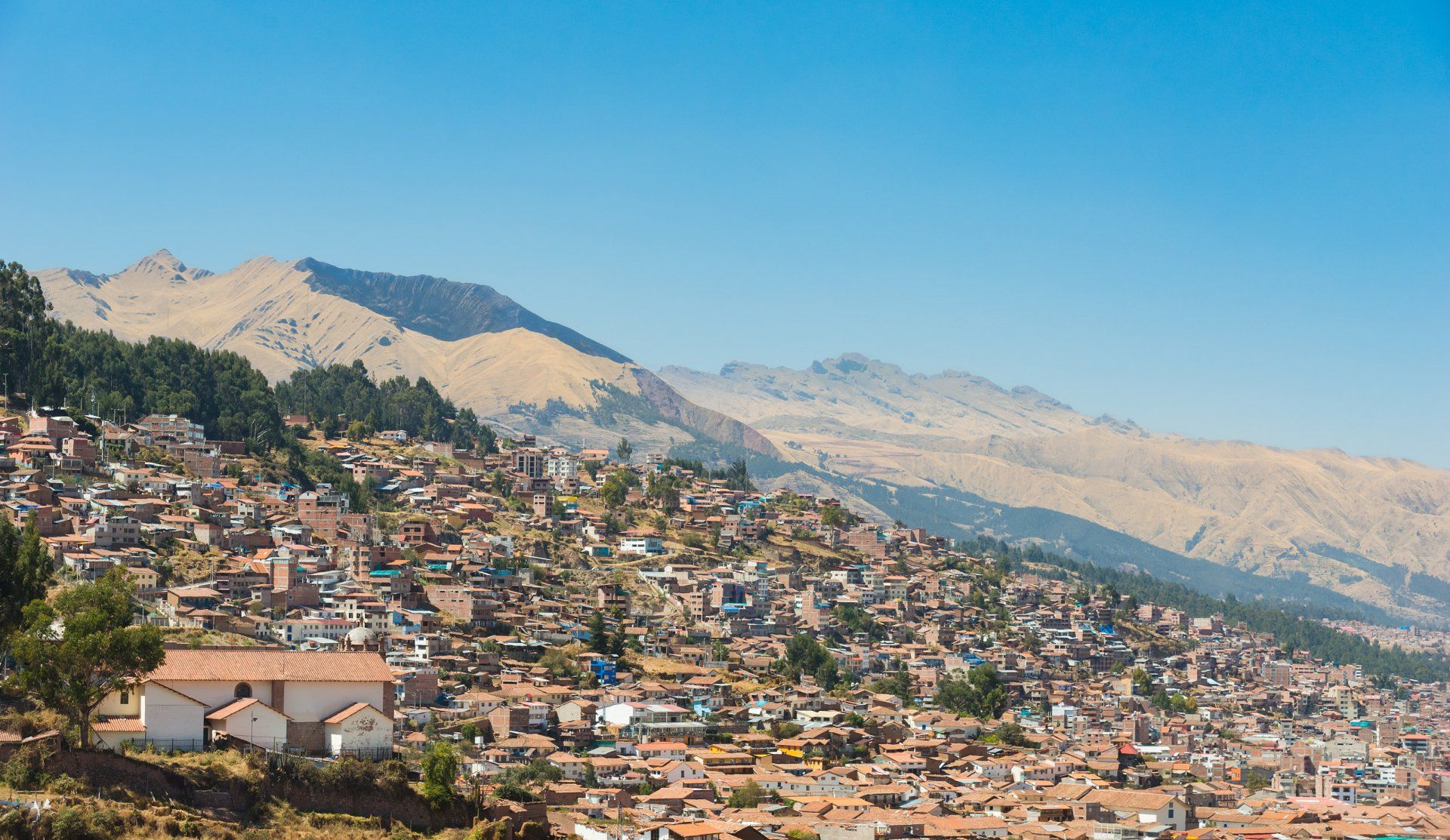 A city sitting on top of a hill with mountains in the background.