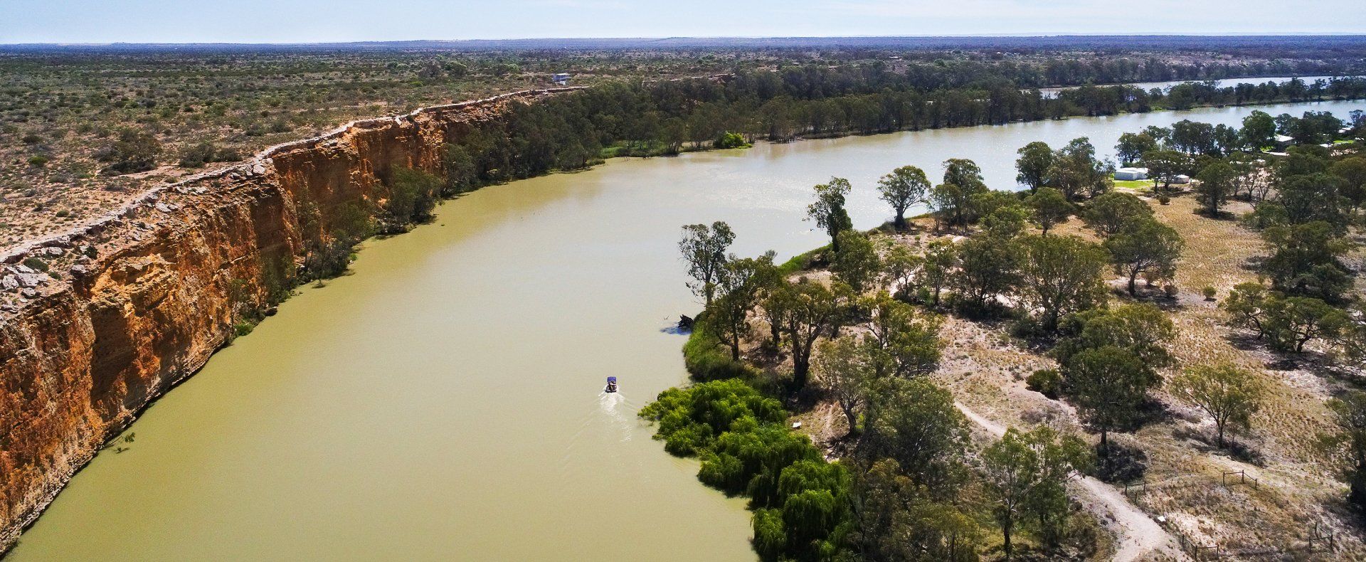 An aerial view of a river surrounded by trees and cliffs.