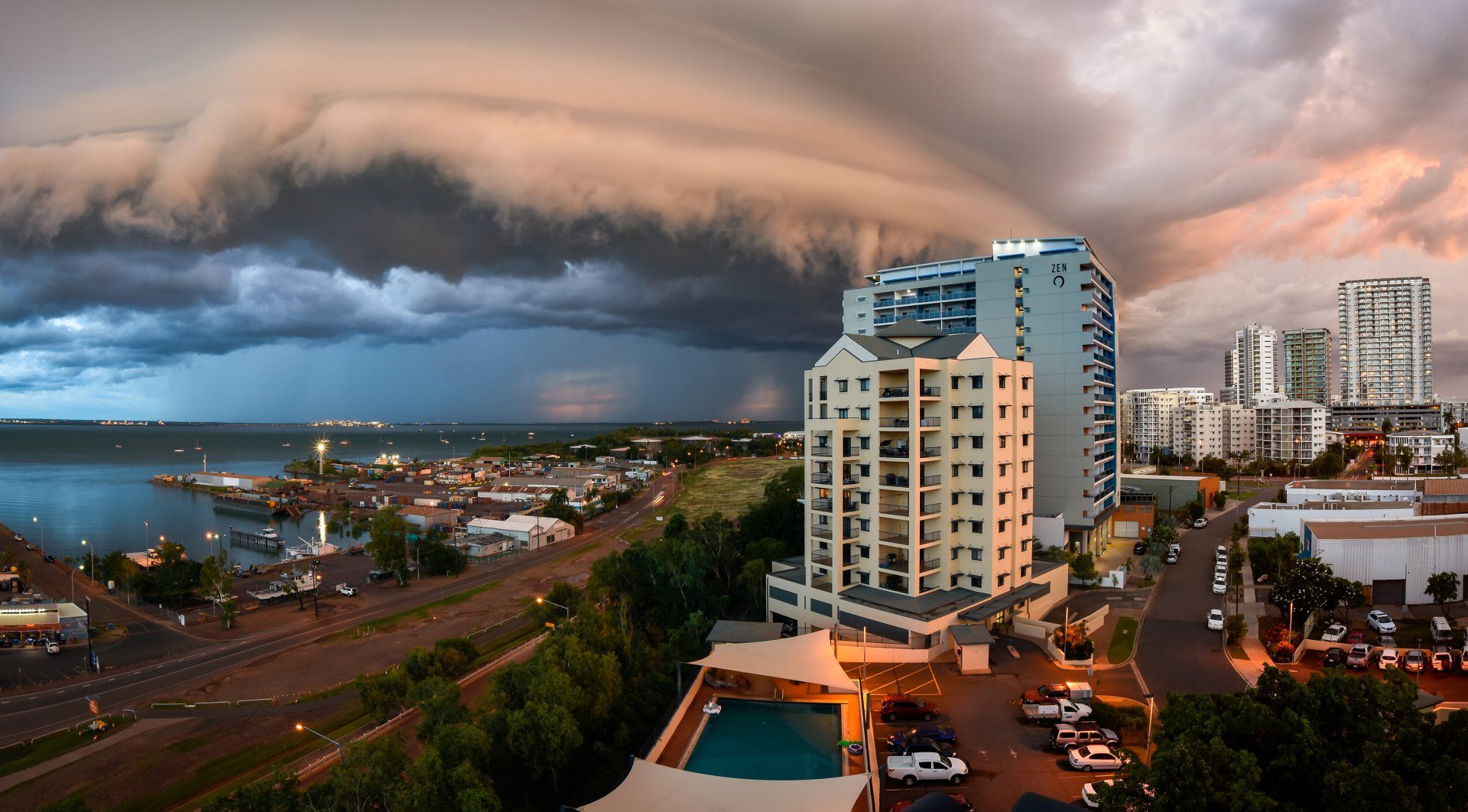 An aerial view of a city with a large cloud in the sky.