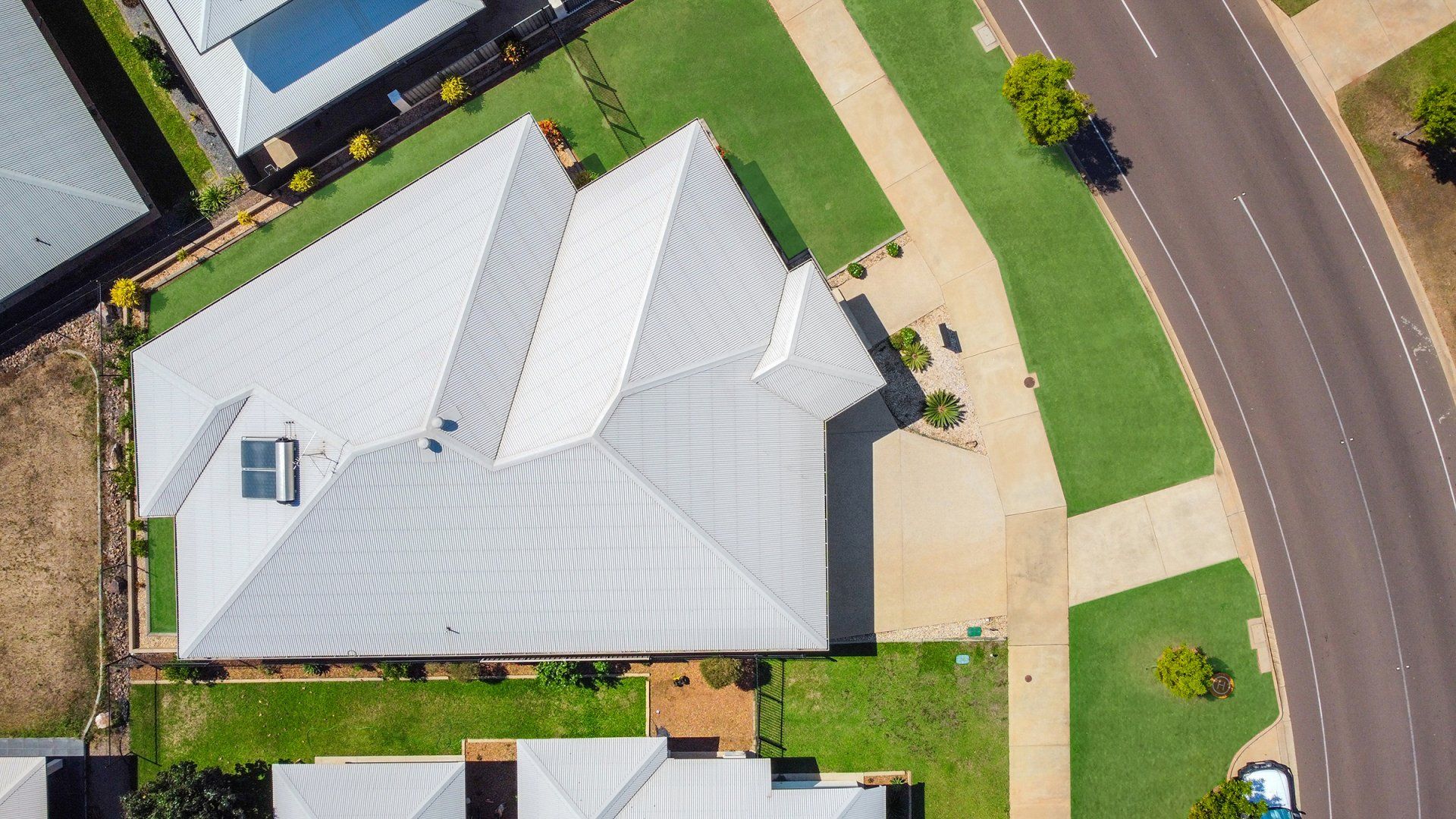 An aerial view of a house with a white roof in a residential area.