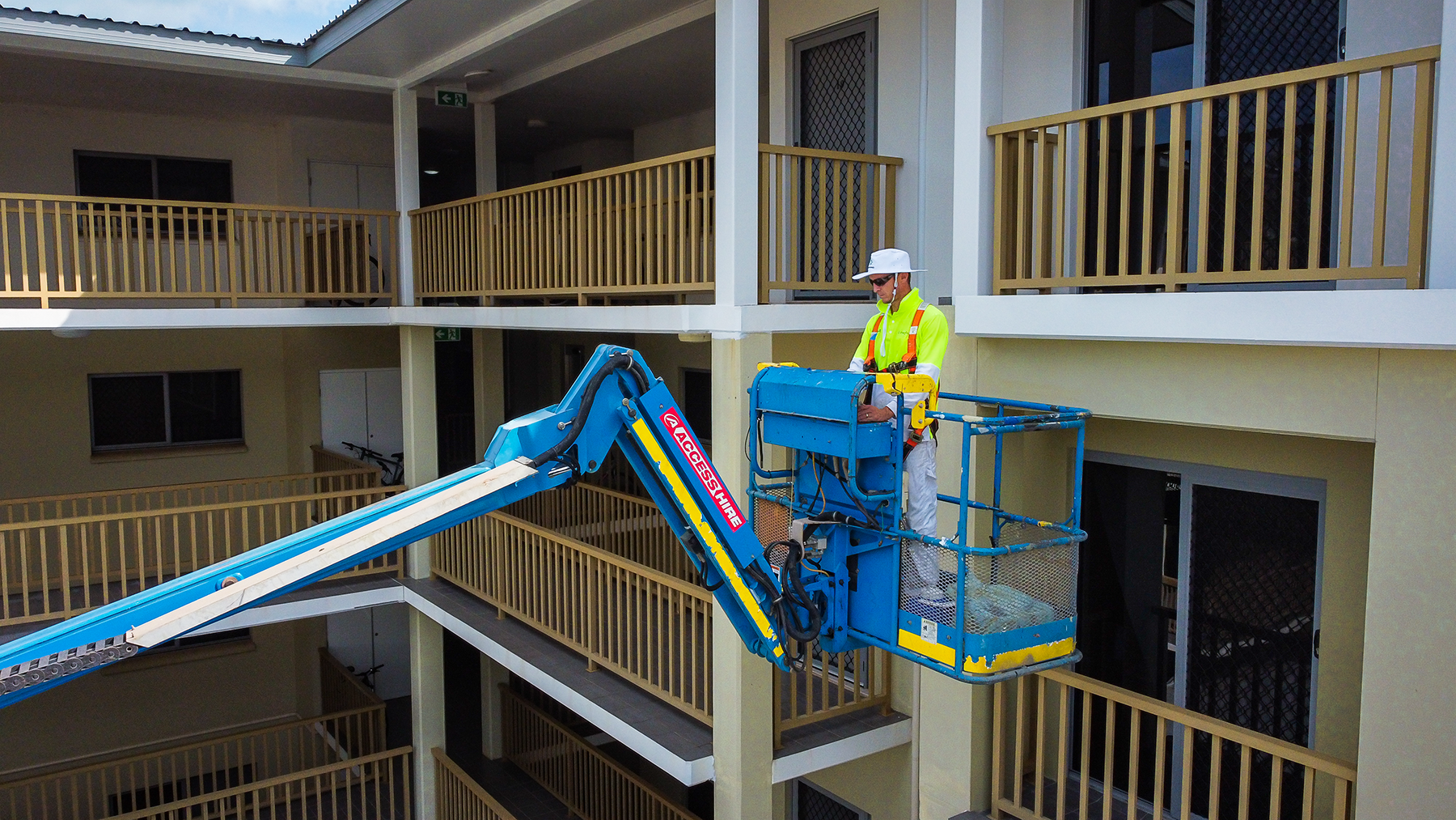 A man is standing on a lift on the side of a building.