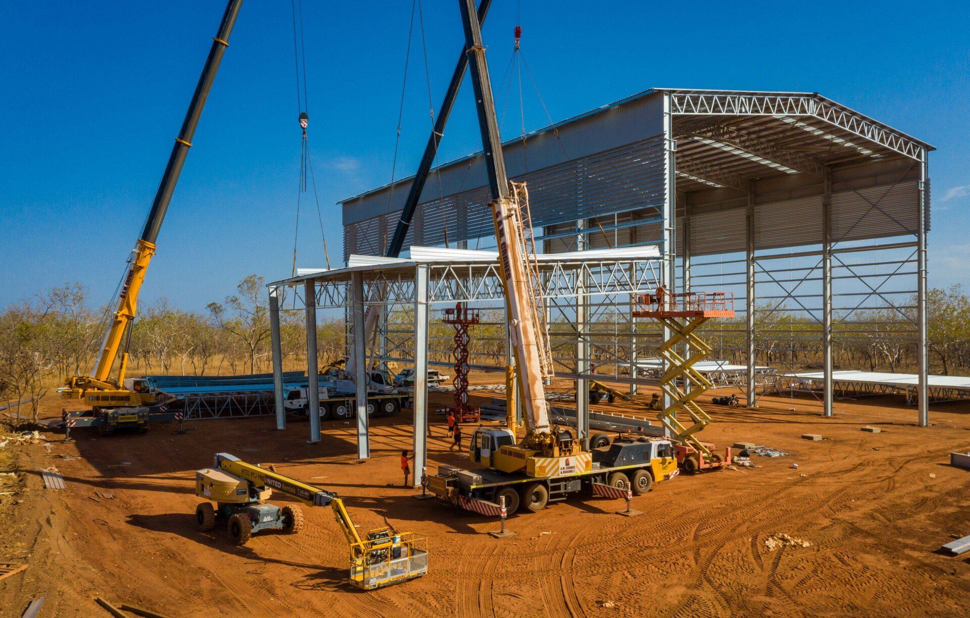 A large building is being built in the middle of a dirt field.