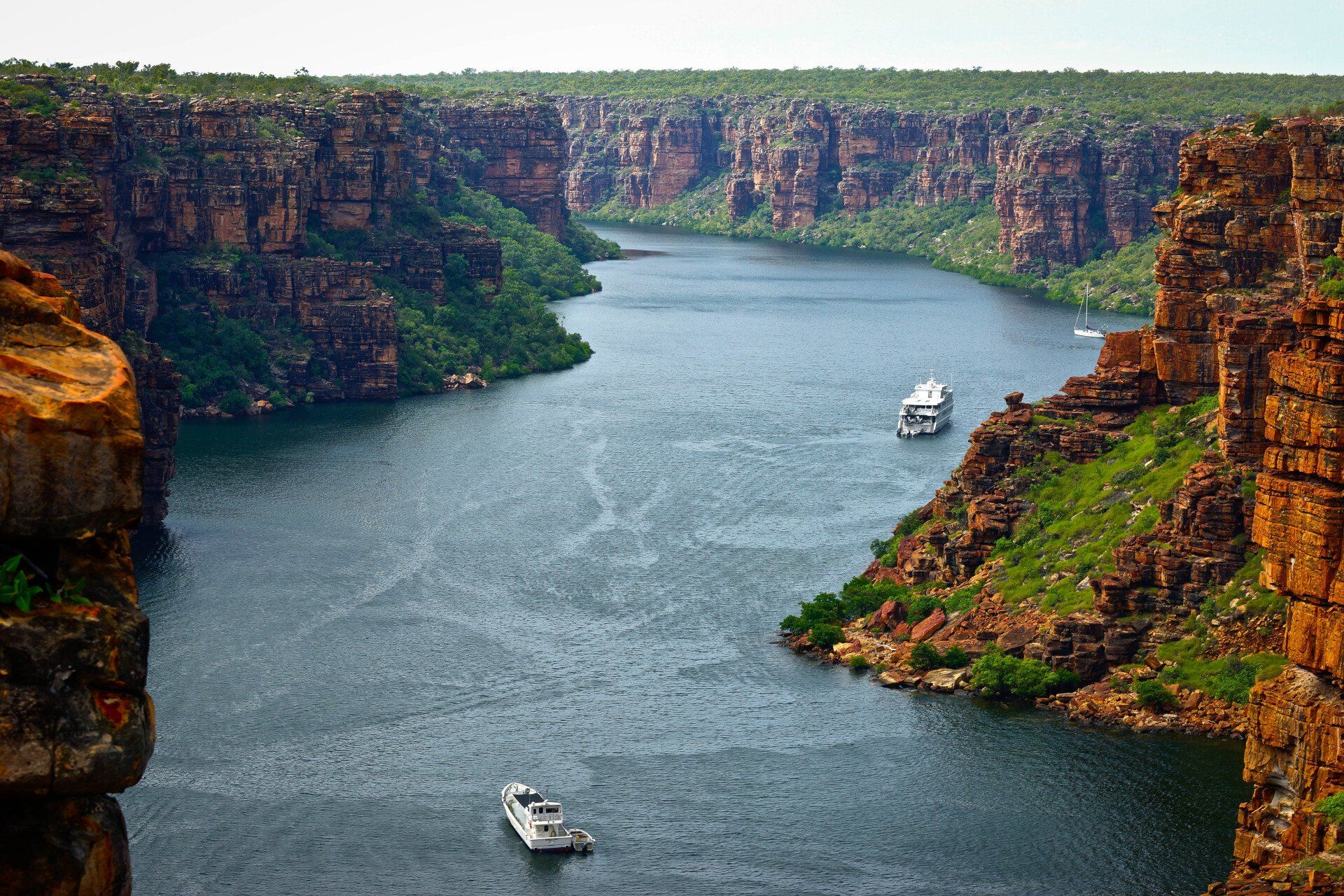 A boat is going down a river between two cliffs.