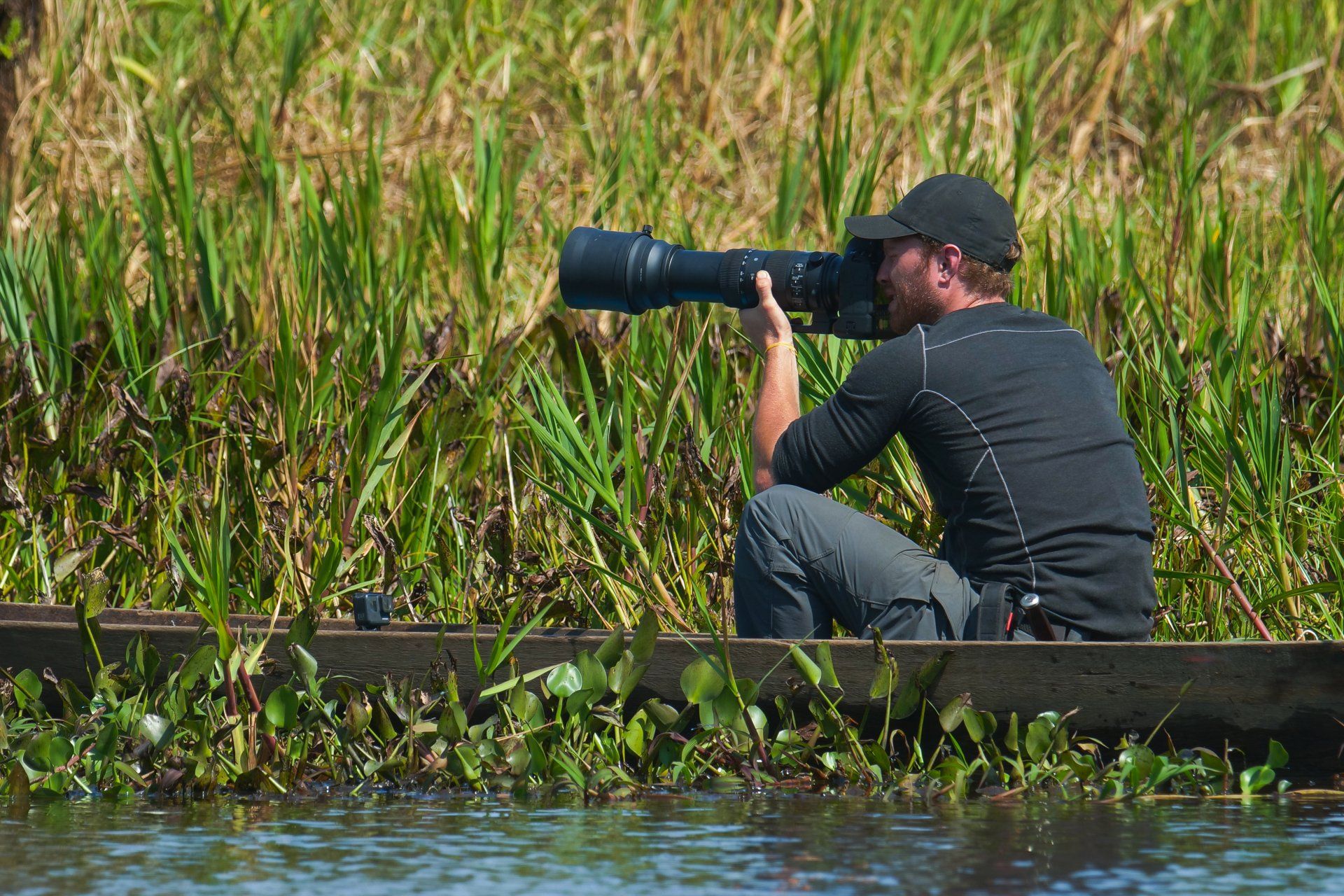 A man is sitting in a boat taking a picture with a camera