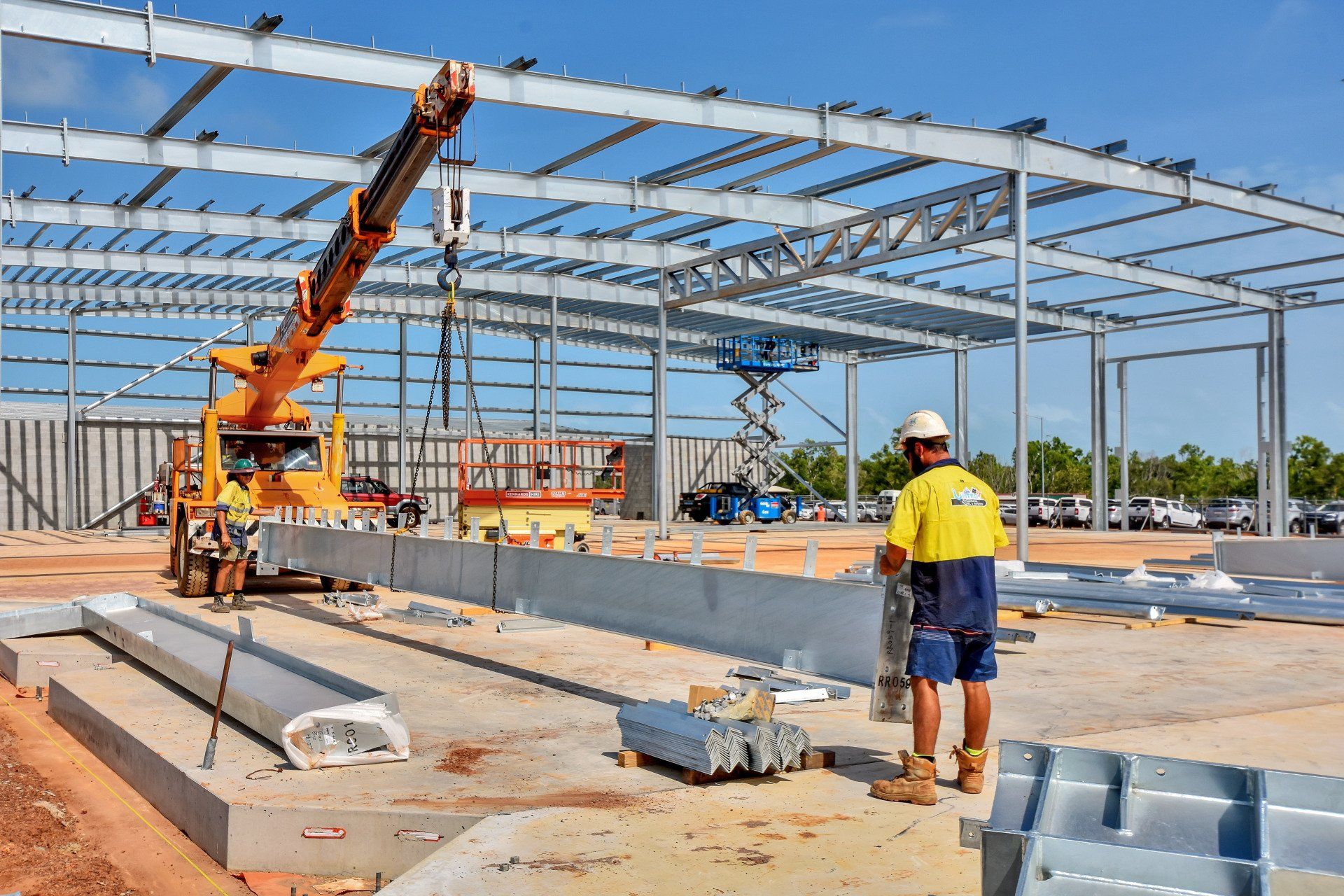 A construction worker is standing in front of a building under construction.