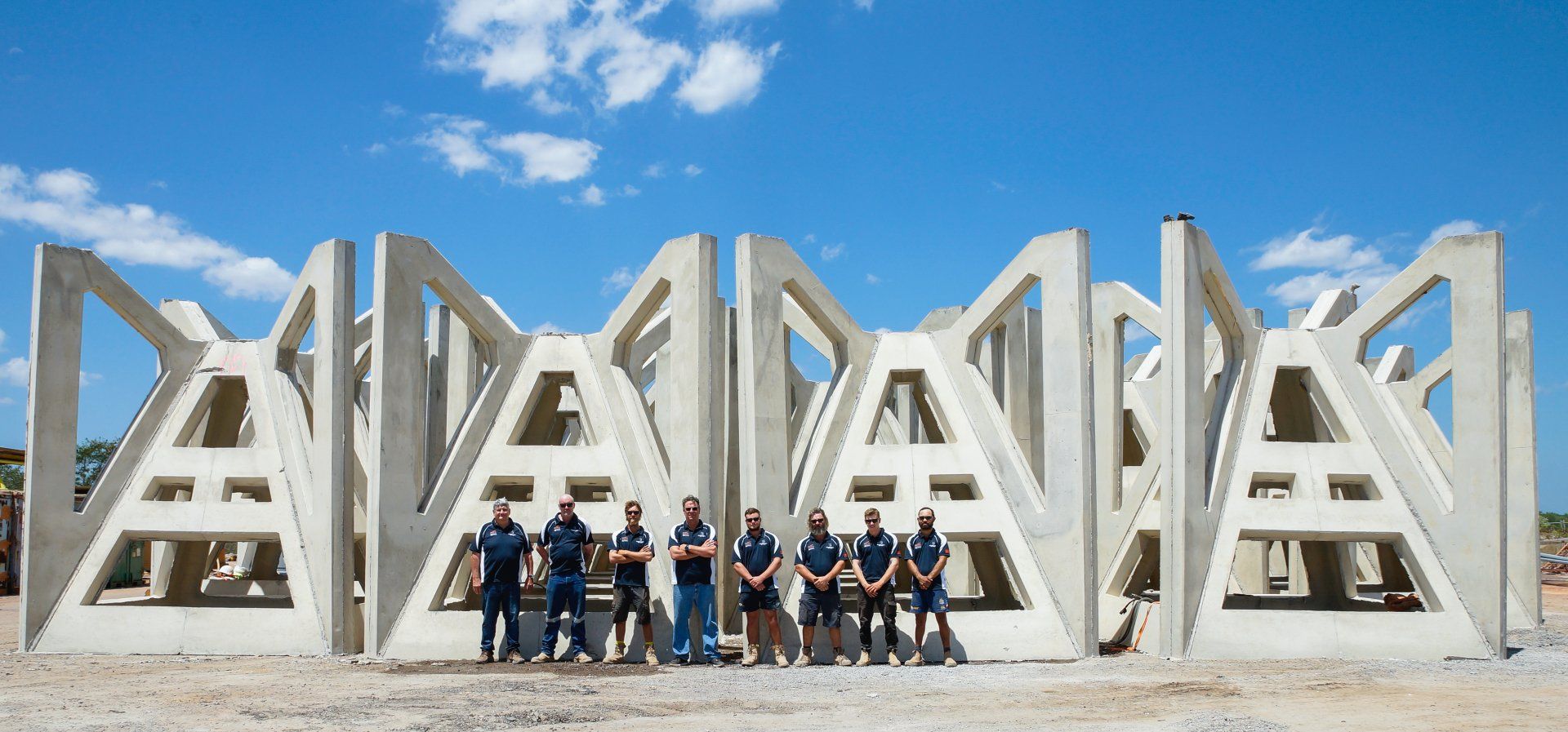 A group of people standing in front of a row of concrete blocks.