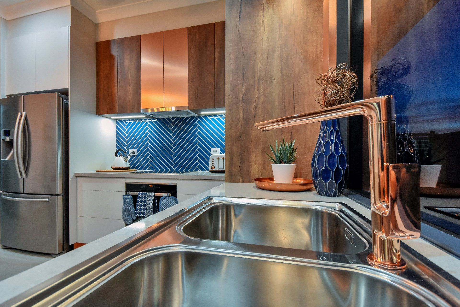 A kitchen with a stainless steel sink and a copper faucet.