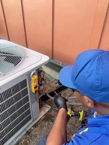 A man in a blue hat is working on an air conditioner.