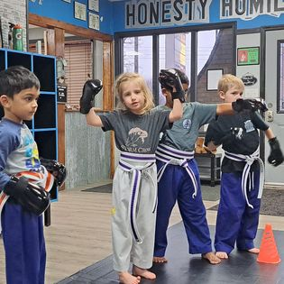 A group of young children are practicing martial arts in a gym.