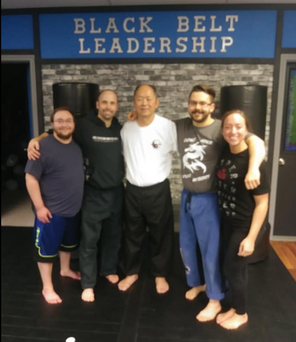 A group of people pose in front of a sign that says black belt leadership
