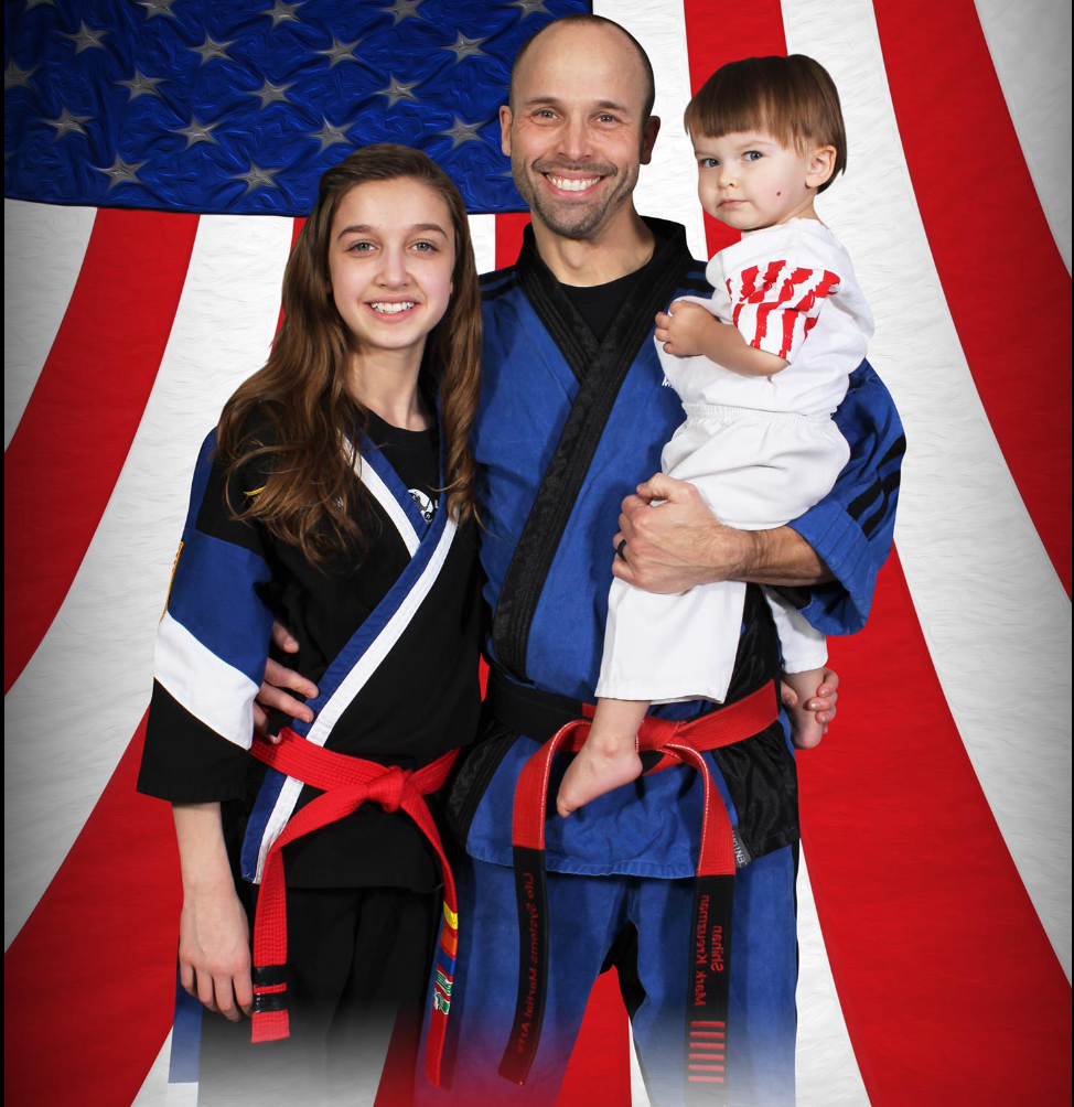 A man is holding a child in front of an american flag