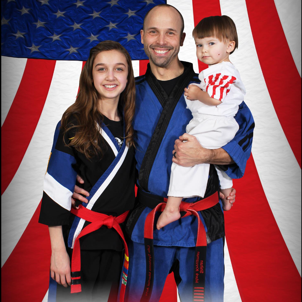 A man is holding a child in front of an american flag