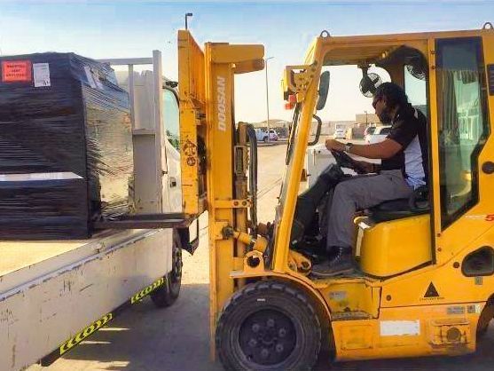a man is driving a yellow forklift next to a truck .