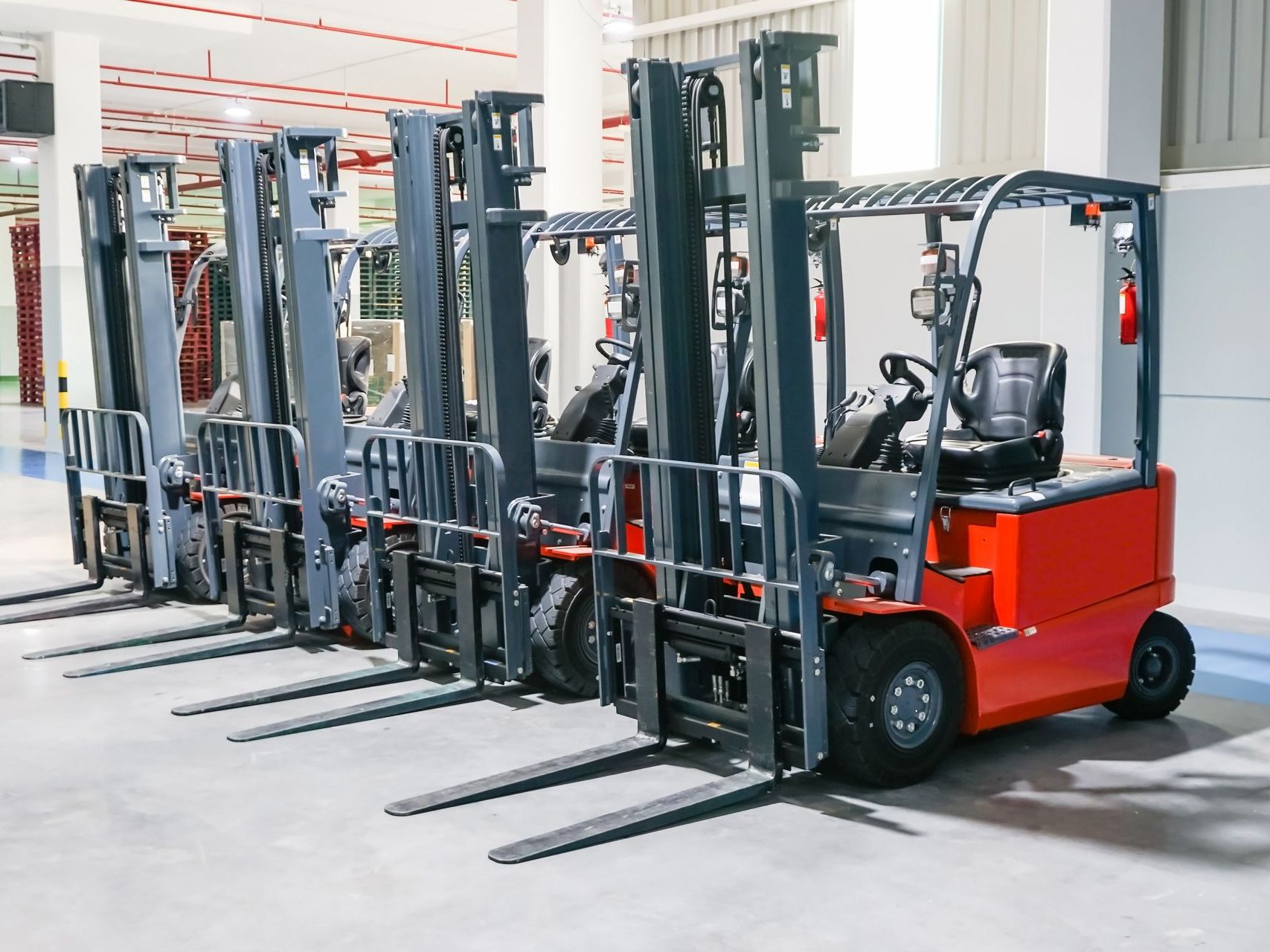 a row of forklifts are parked in a warehouse .