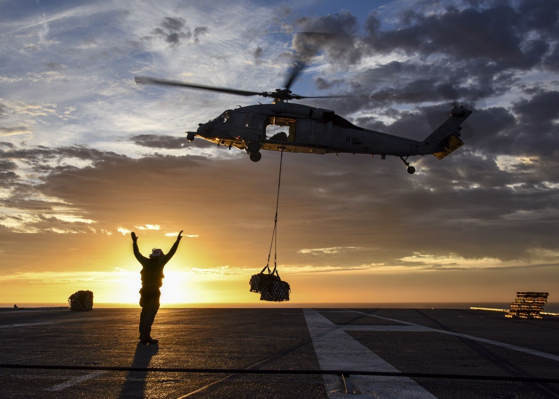 a helicopter is flying over a man on a runway at sunset