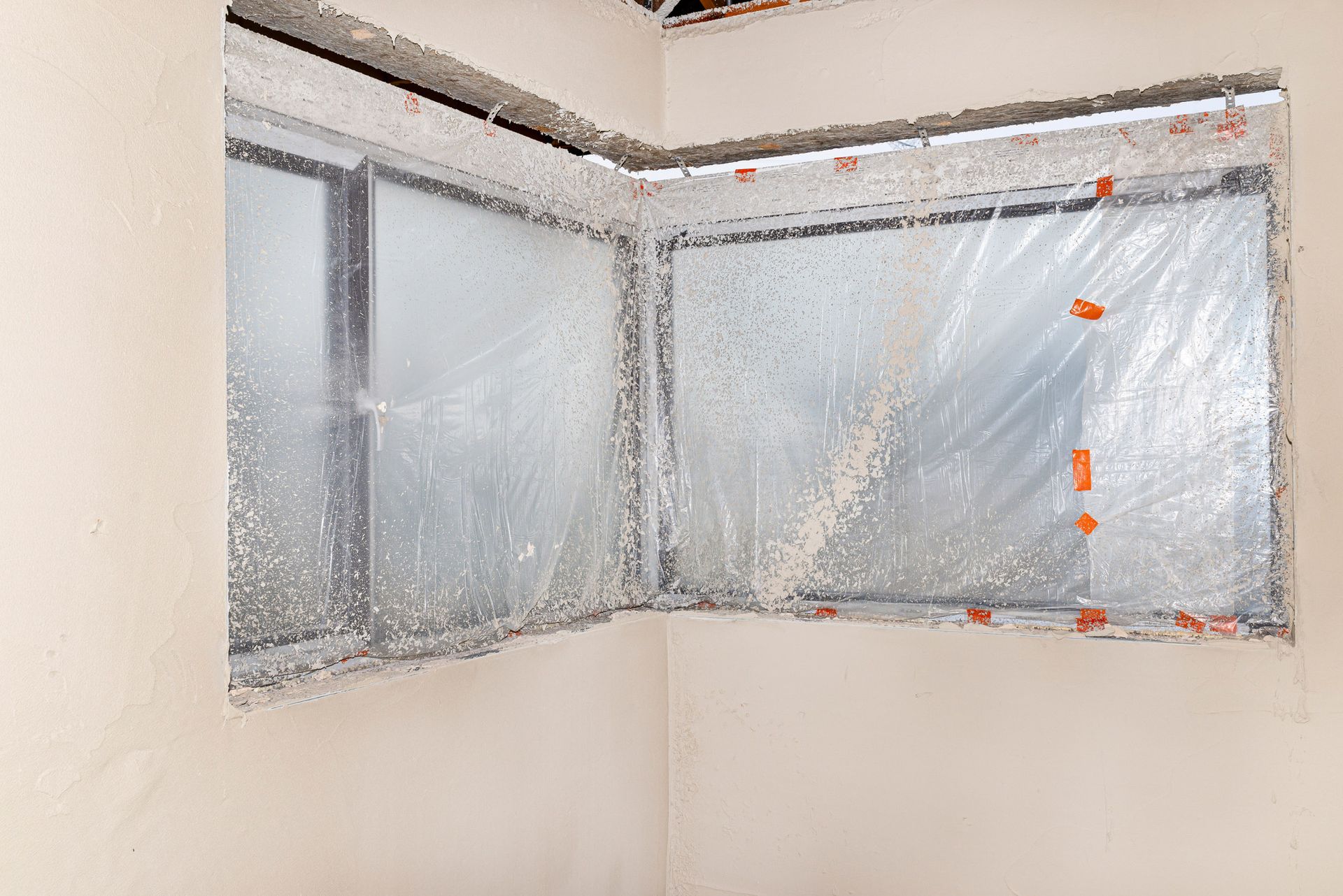 An empty room with a window covered in plastic.