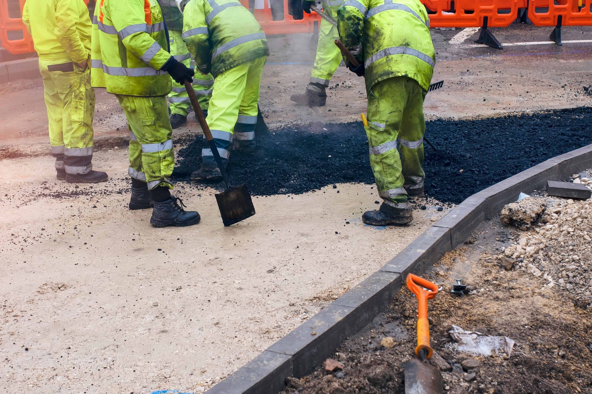 A group of construction workers are working on a road.