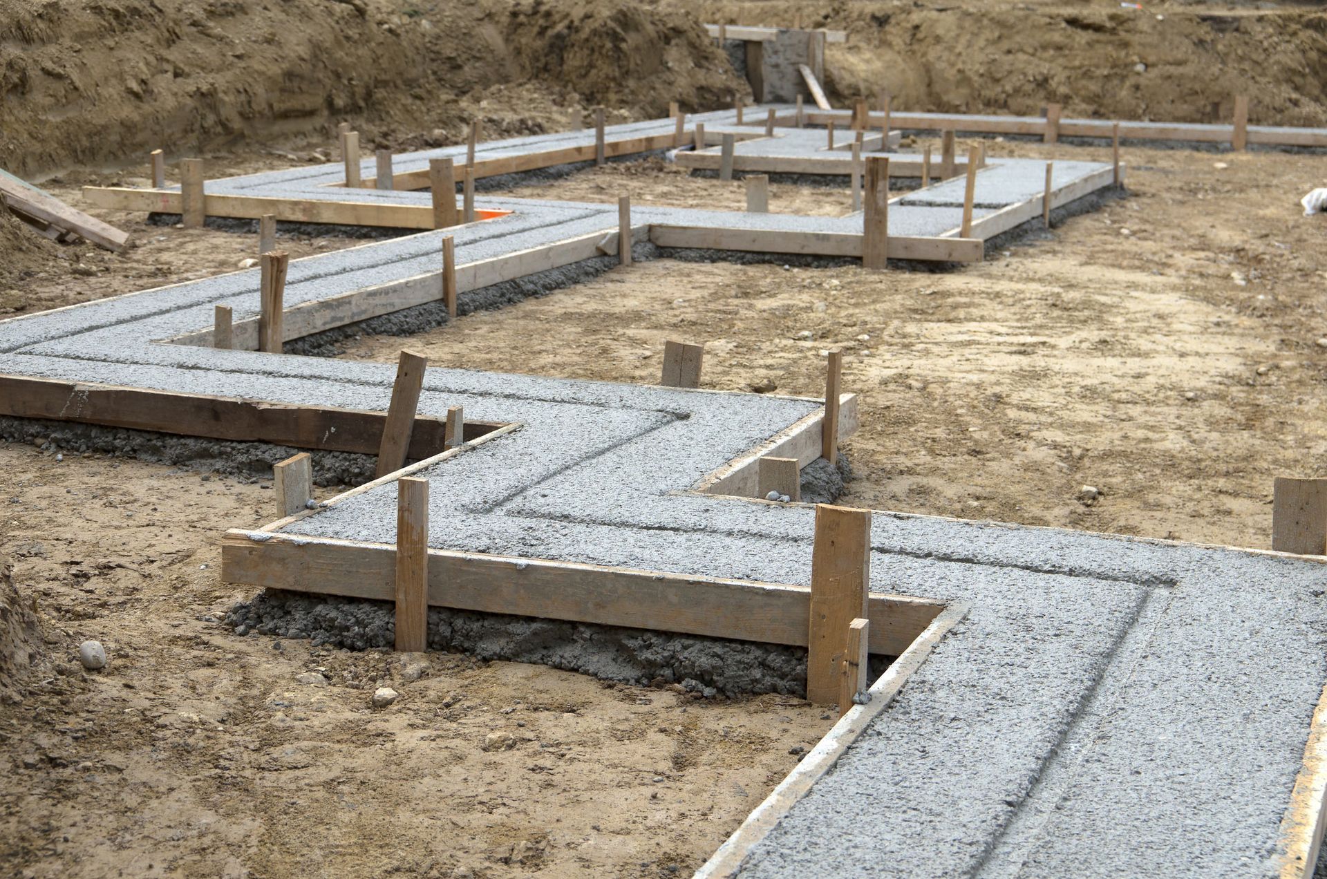 A concrete foundation is being built in a dirt field.