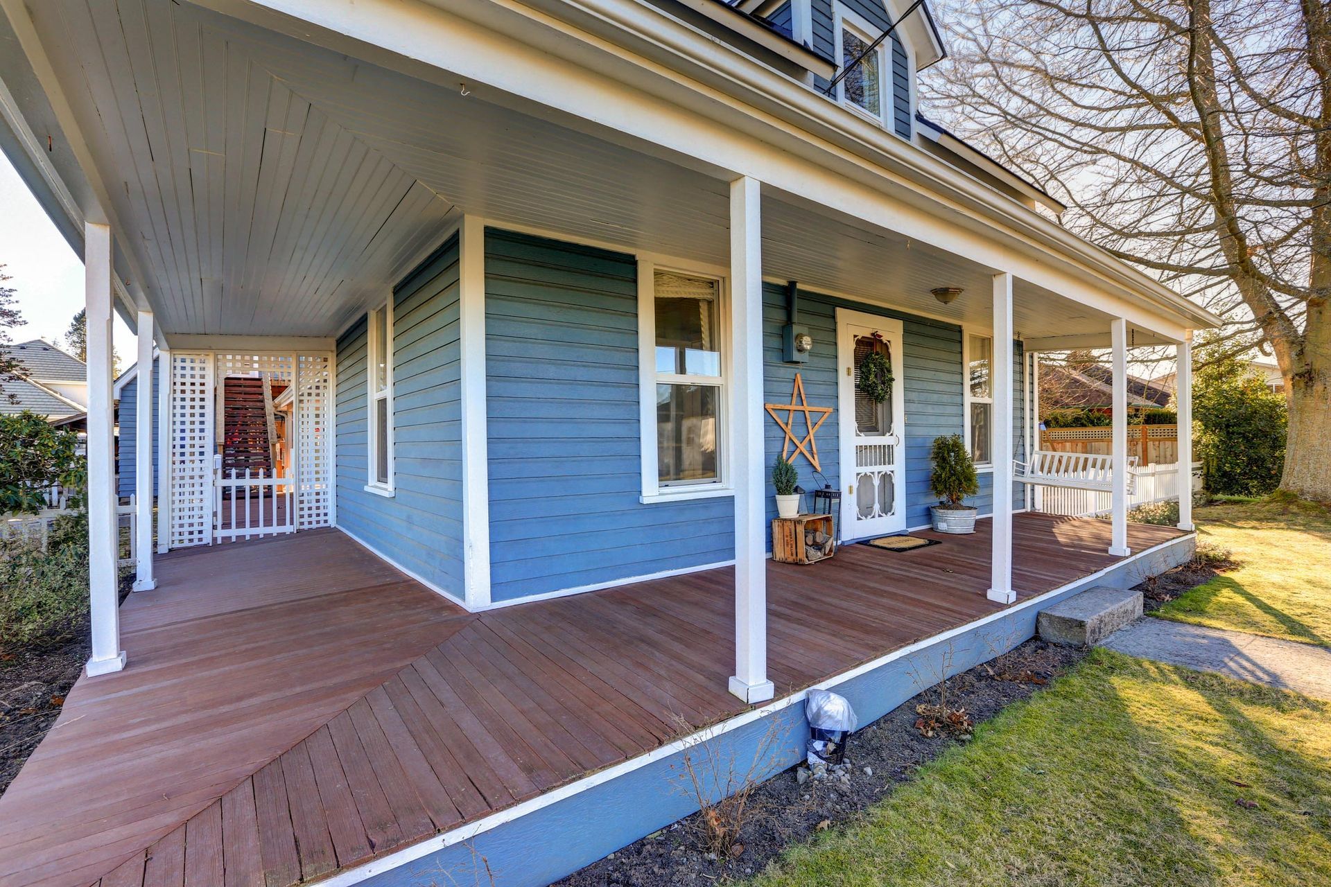 A blue house with a porch and a wooden deck.