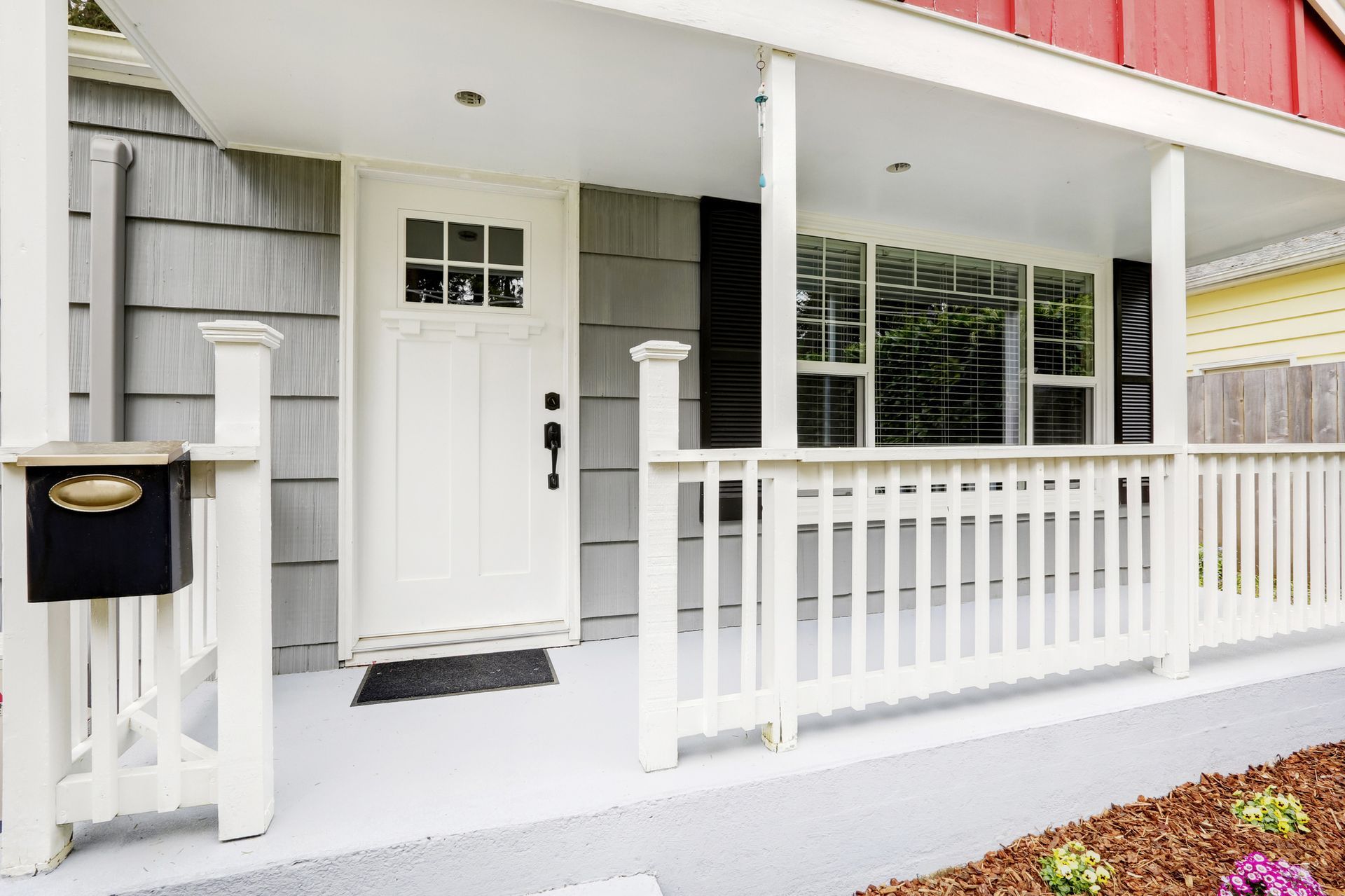 A porch with a white railing and a black mailbox.