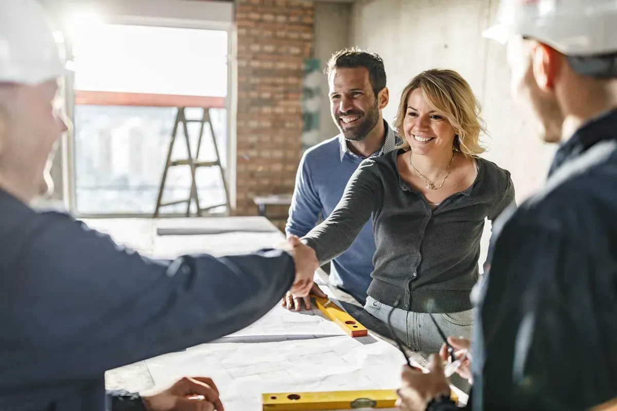 Flooring contractor shaking a smiling client's hand.