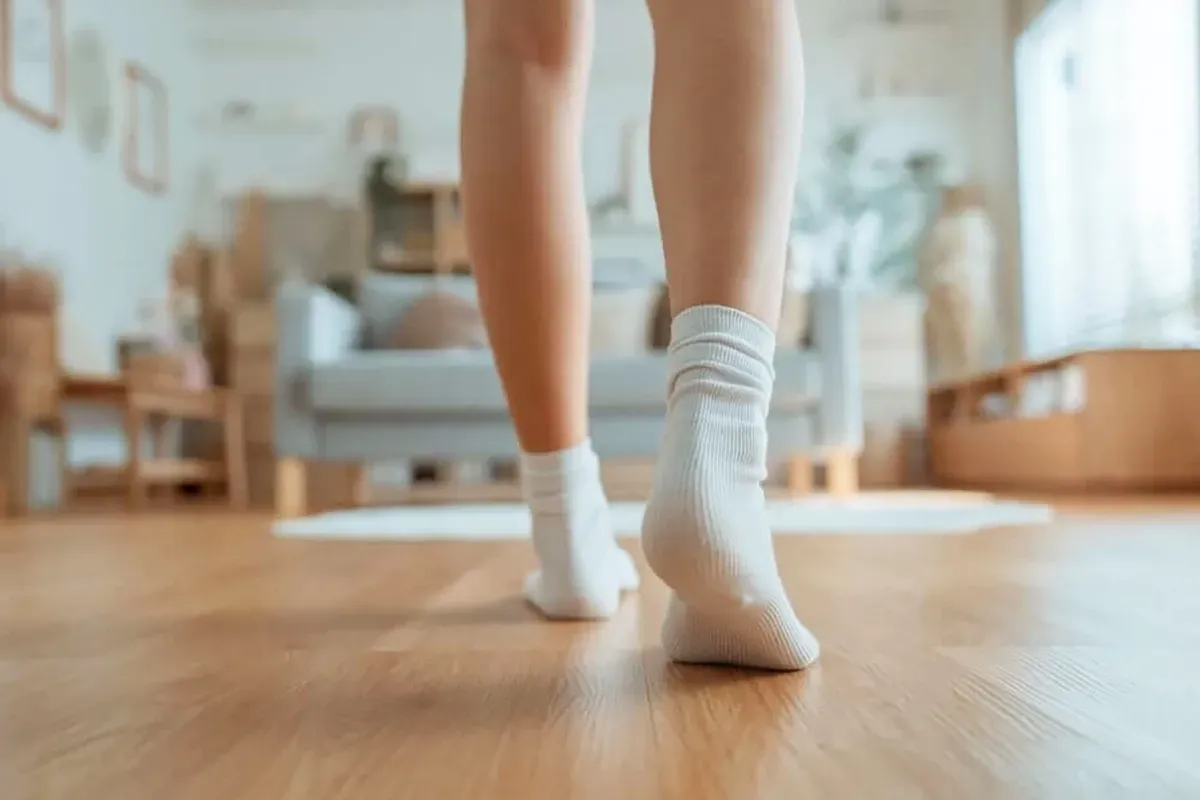 Closeup of a person walking around their apartment in socks.