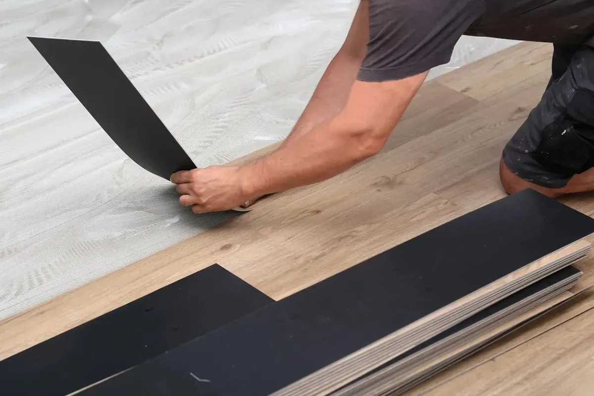 Man laying vinyl plank flooring.