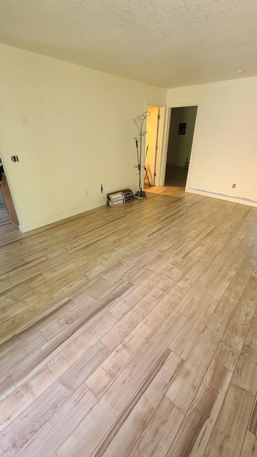 An empty kitchen with hardwood floors and a refrigerator.