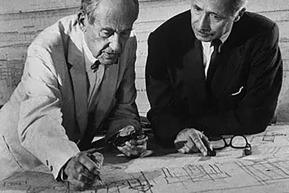 A black and white photo of two men looking at a blueprint.