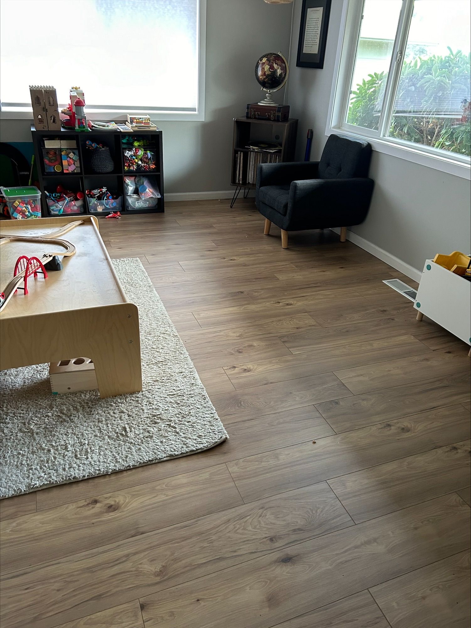 An empty kitchen with hardwood floors and a refrigerator.