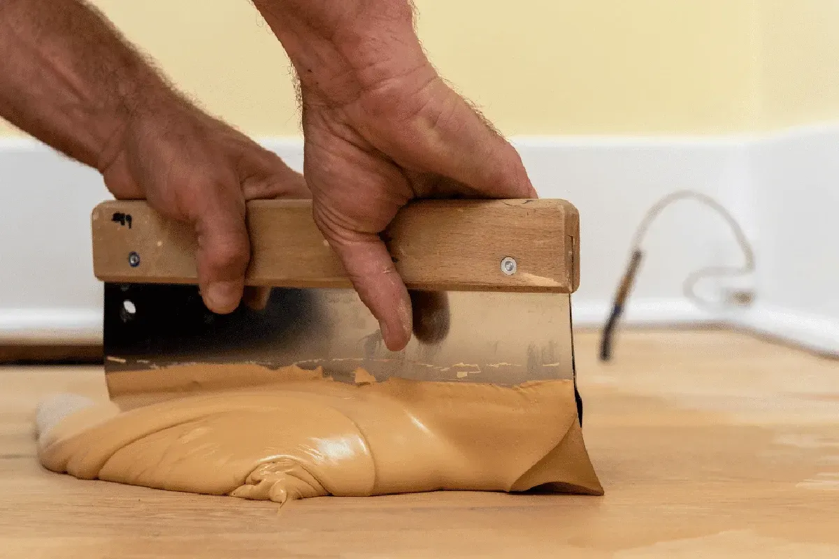 Applying wood floor filler.